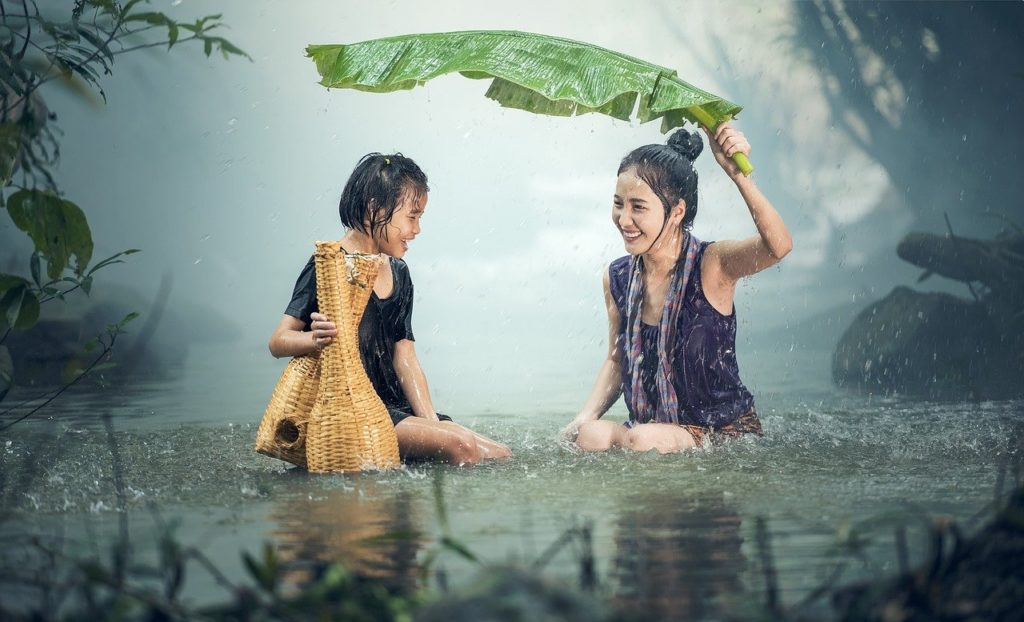 土砂降りの雨で葉っぱの傘をさす女性