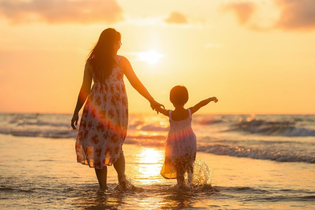 夕日と海を見る母と子供