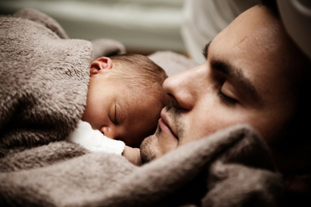 小さな息子と毛布で寝る父