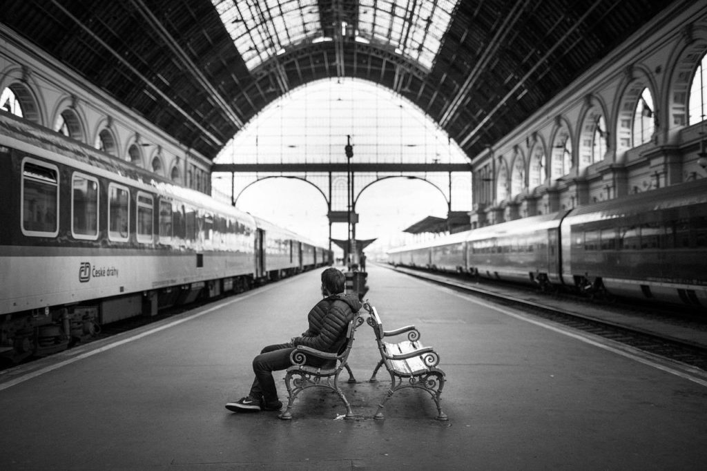 駅で電車を待つ男性の白黒写真