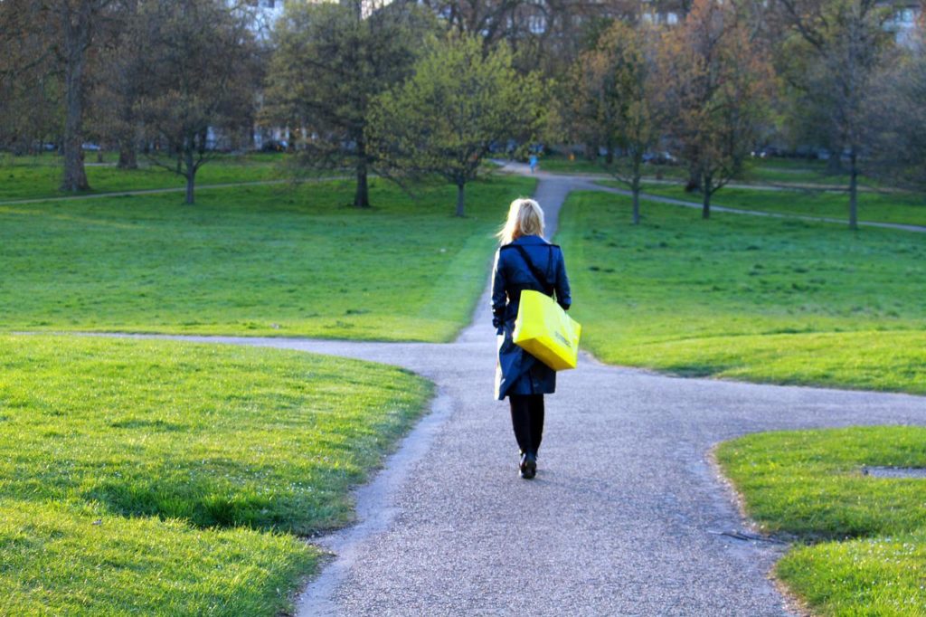 黄色い紙袋を持って分かれ道を歩く女性