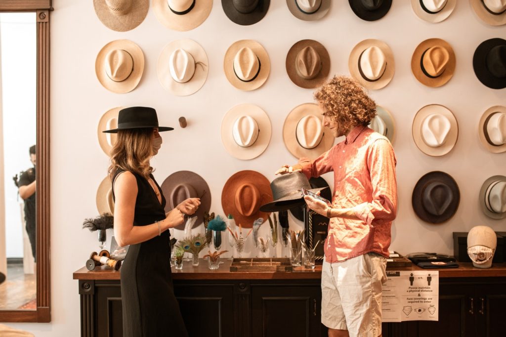並ぶ帽子を選んでいる女性と男性店員