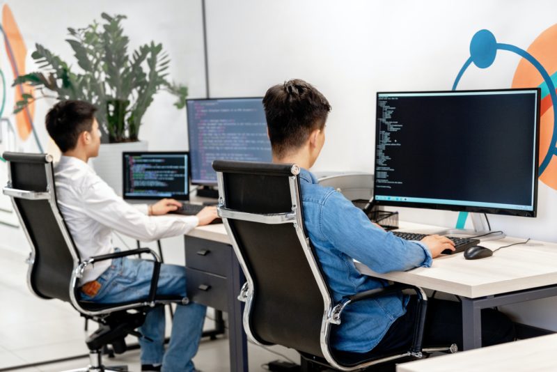 会社でパソコンの画面を眺める男性たち