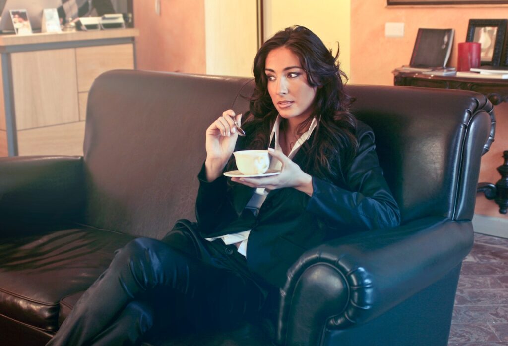ソファに座ってゆっくり休んコーヒーを飲む女性