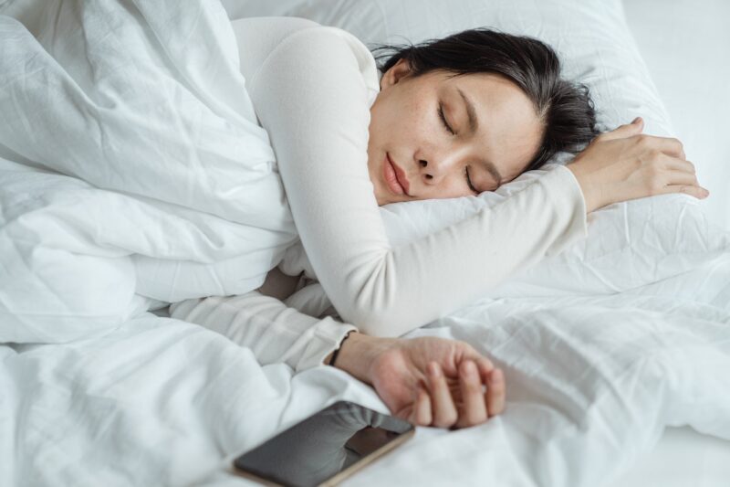 スマートフォンを横に置いて寝ている女性