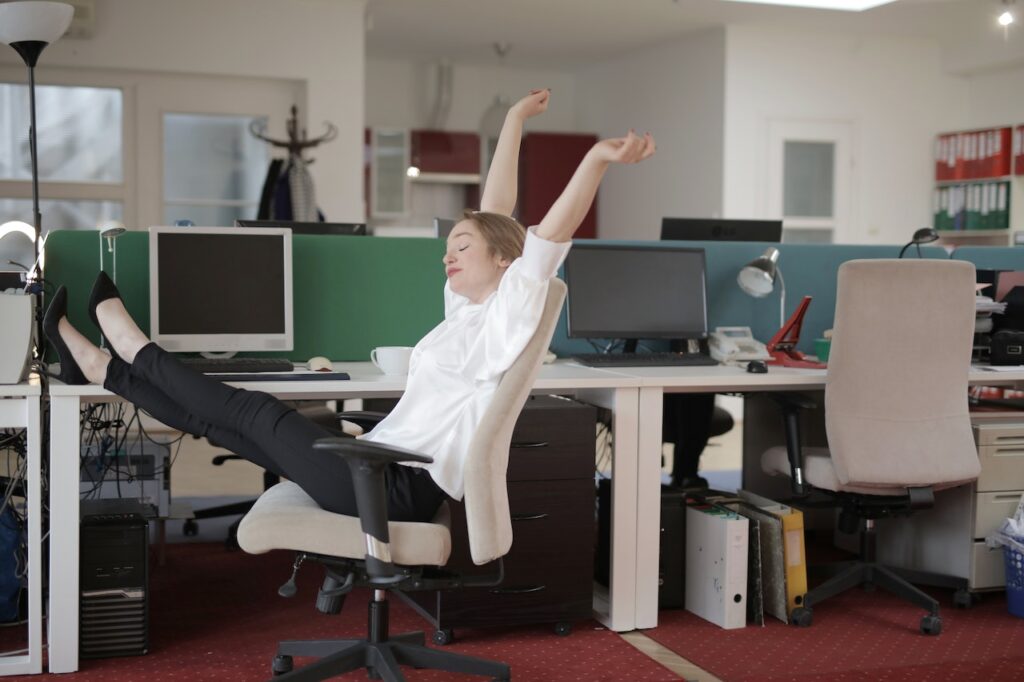 社内で机に足を上げて大きく伸びをしている女性