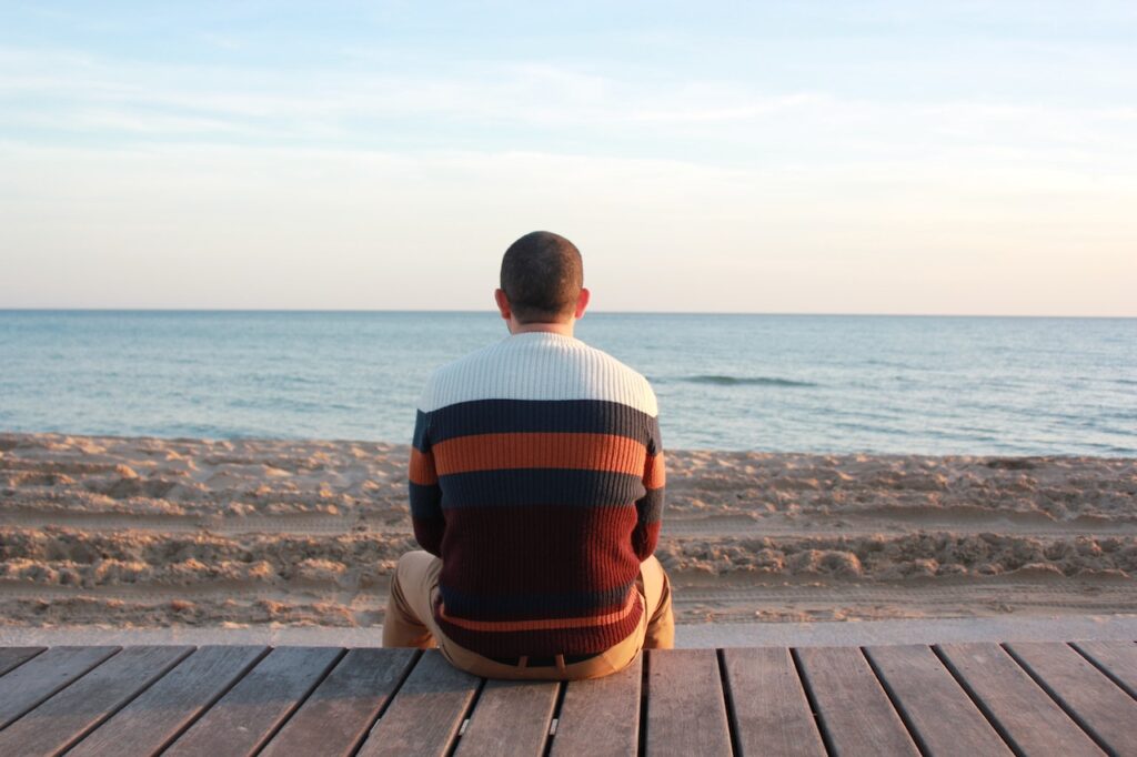 砂浜に1人で座って海を眺める男性