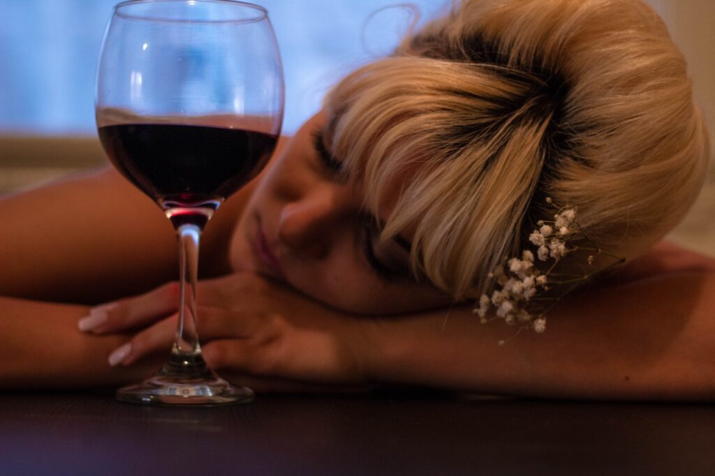 ワインを揺らして机で寝ている女の人