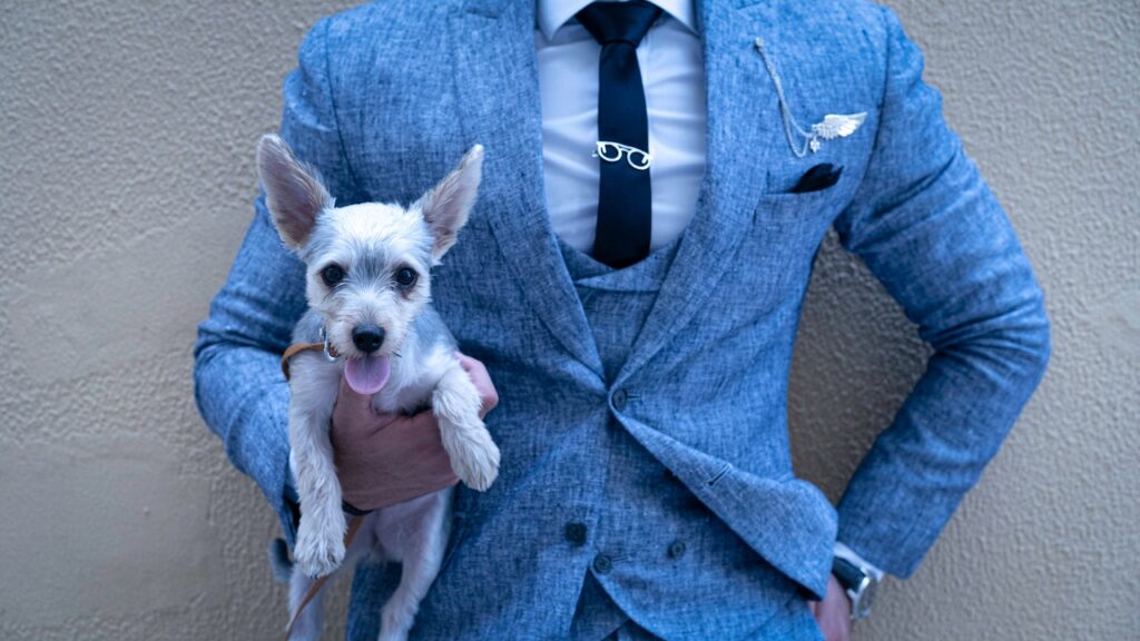 青のスーツで小脇に子犬を抱えている男性