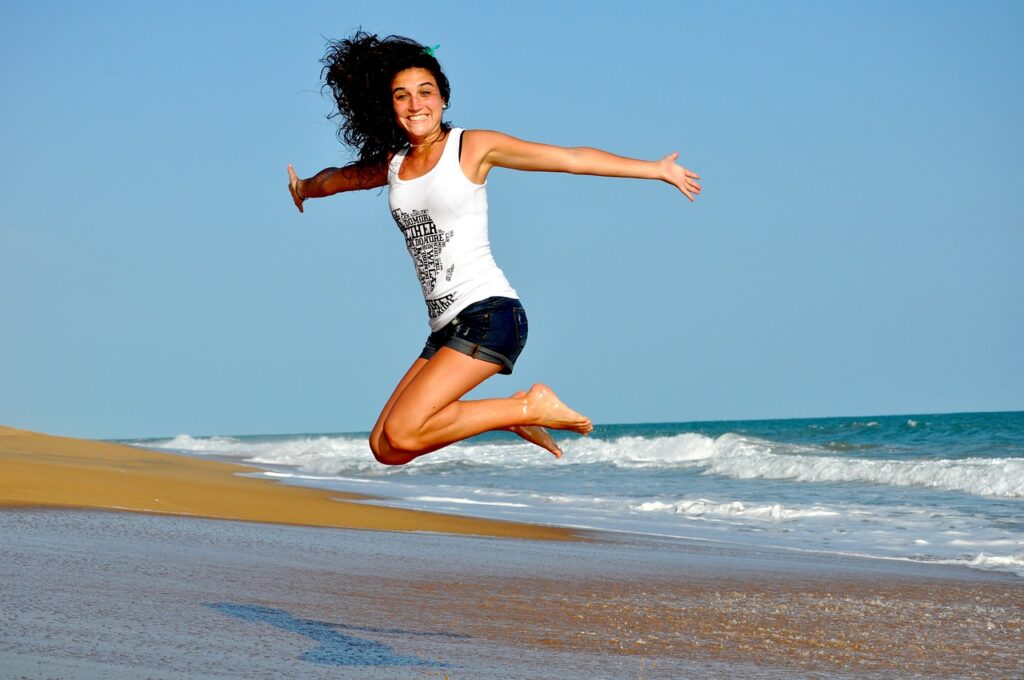 海で高くジャンプして笑っている女性