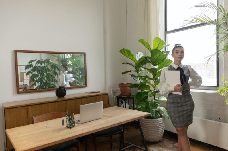 観葉植物が置いてある綺麗なオフィスで窓際に立っている綺麗な秘書