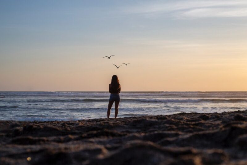 朝焼けの海に一人でたたずんでいる女性