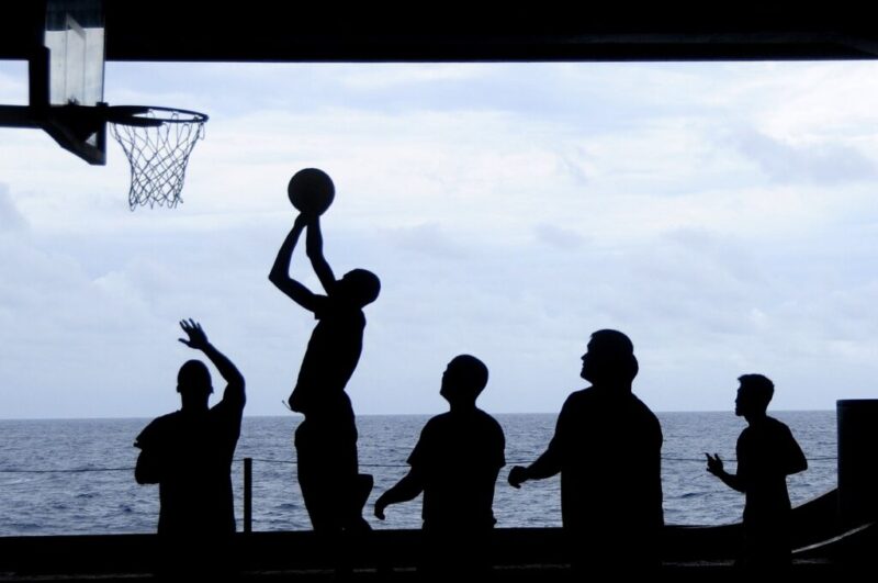 海沿いのバスケットゴールでプレイを楽しんでいる男性たち