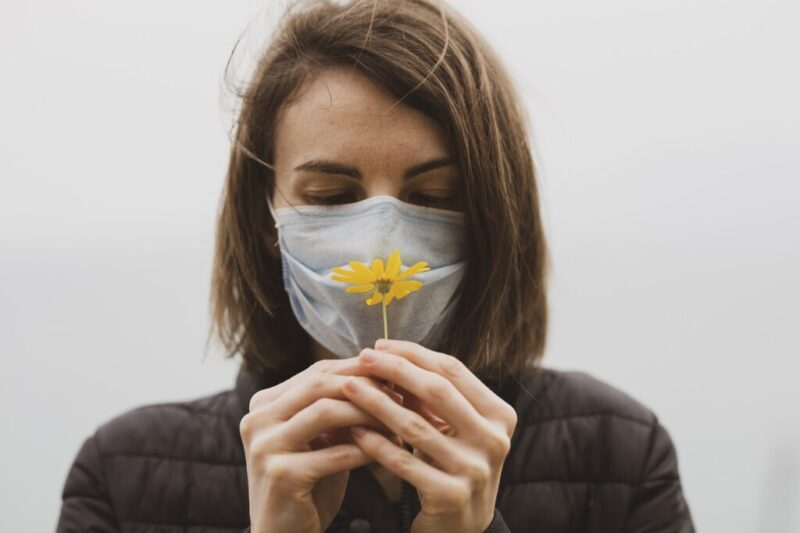 マスク越しに花の匂いを嗅ぐ女性