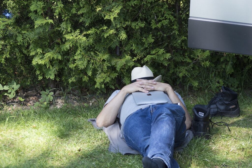 本を顔において芝生で寝る男性