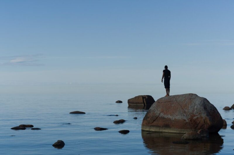 海岸の大きな岩の上に立つ男性