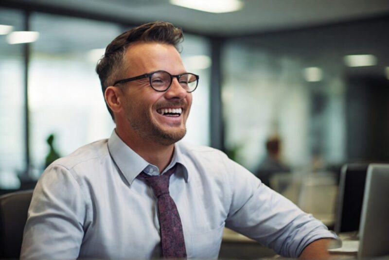 笑顔で笑っている会社内にいるシャツを着てネクタイをしている男性